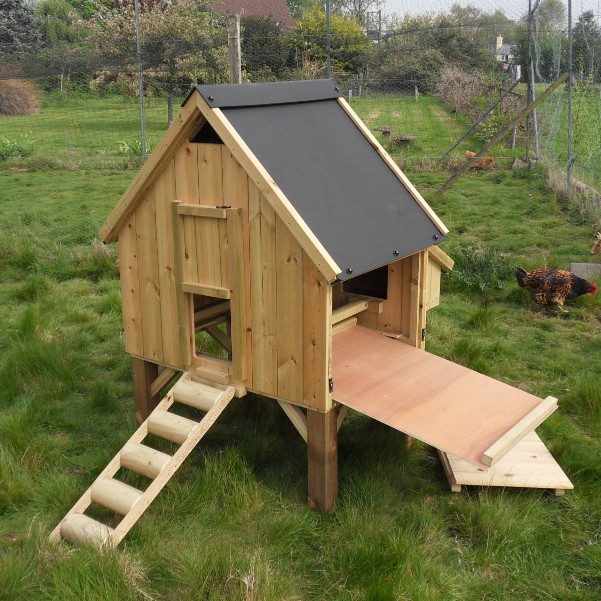 A wooden chicken coop with its floor slid out for cleaning