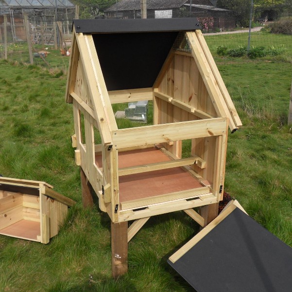 A small chicken coop with its sides and roof removed to show the internal detail