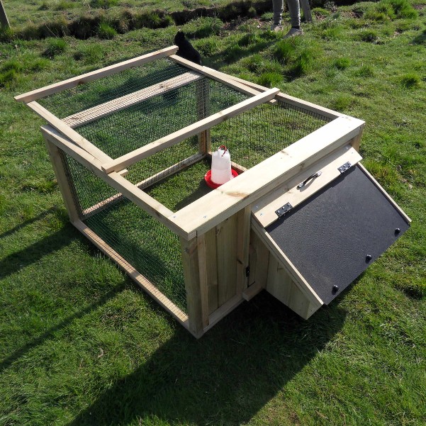 A broody coop with a plastic drinker in the run area